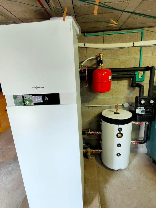 Système de chauffage blanc avec réservoir d'eau et vase d'expansion rouge, installé au sous-sol