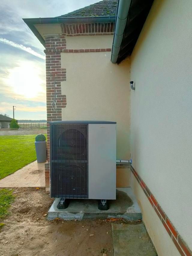 Unité de pompe à chaleur à l'extérieur d'une maison aux murs beiges et en briques