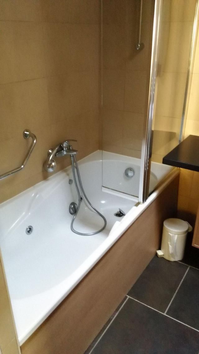 Baignoire blanche avec douchette dans une salle de bains carrelée