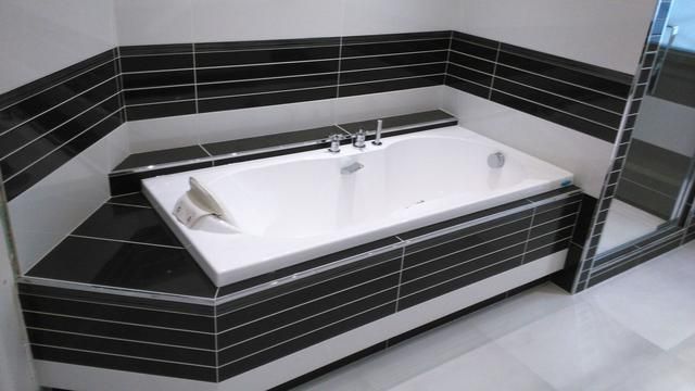 Salle de bains moderne avec baignoire jacuzzi blanche entourée de carreaux noirs et blancs