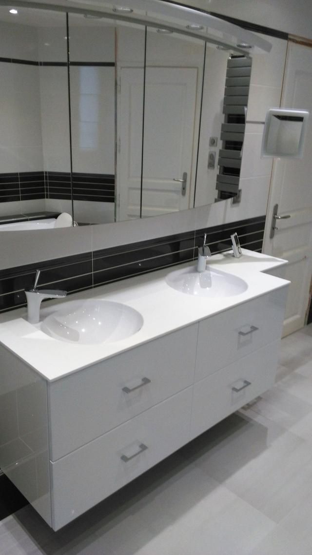 Meuble-lavabo double blanc avec robinetterie et poignées de tiroir chromées, sous un miroir et un mur carrelé de noir