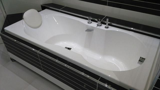 Baignoire blanche encastrée dans une salle de bains avec carrelage noir