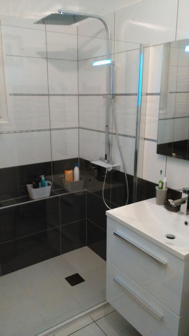 Salle de bains moderne avec carrelage noir et blanc, pommeau de douche et meuble-lavabo blanc