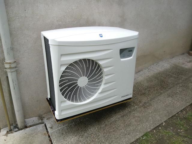 Pompe à chaleur extérieure blanche fixée sur un mur en béton