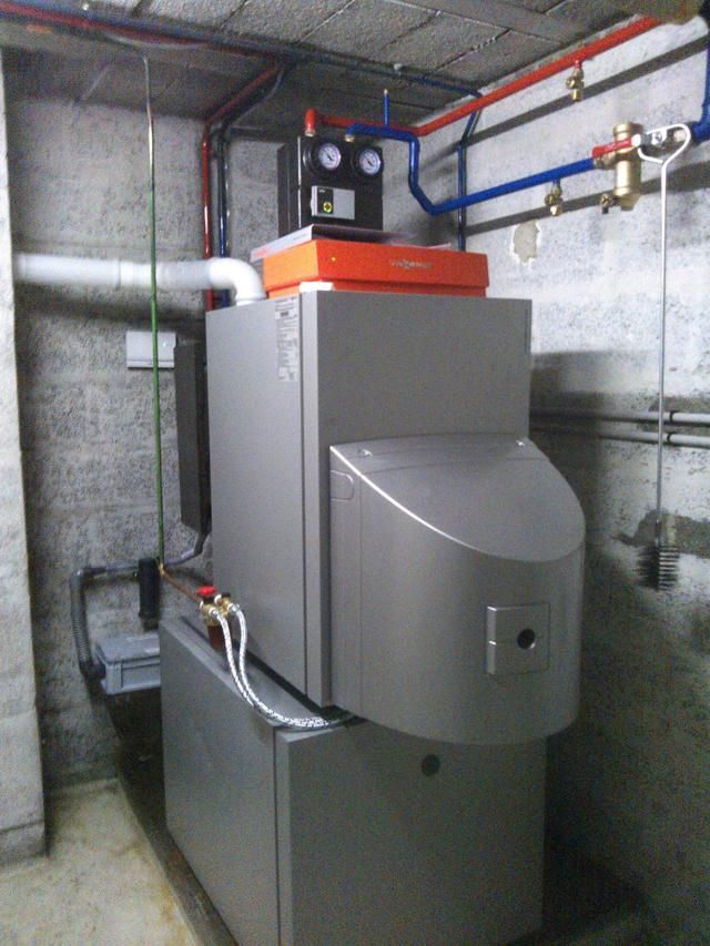 Fournaise grise au sous-sol, avec tuyaux et manomètres sur les murs