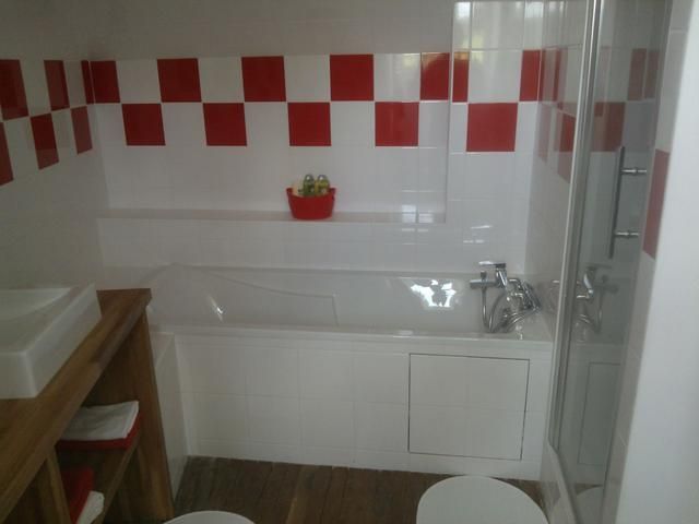 Salle de bains avec carrelage à damier rouge et blanc, baignoire et douche