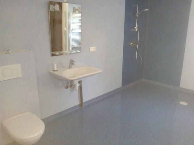 Salle de bains accessible avec toilettes, lavabo et douche à l'italienne