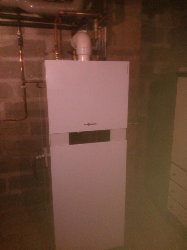 Fournaise à gaz blanche installée dans un sous-sol aux murs en parpaings