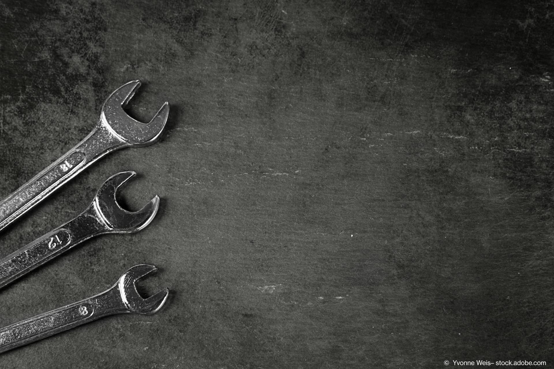 Drei Schraubenschlüssel liegen auf einem schwarzen Untergrund