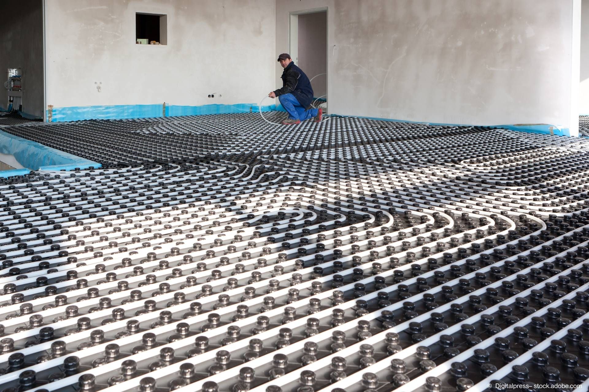 Eine Fußbodenheizung, welche gerader von einer Person installiert wird