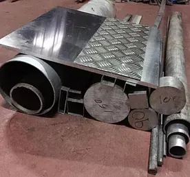 Una pila de tubos y tuberías de metal colocados uno encima del otro sobre un suelo rojo.