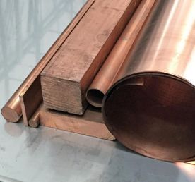 Un montón de tubos y barras de cobre están colocados uno encima del otro sobre una mesa.