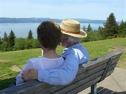 Ein Mann und eine Frau sitzen auf einer Bank und schauen aufs Wasser.