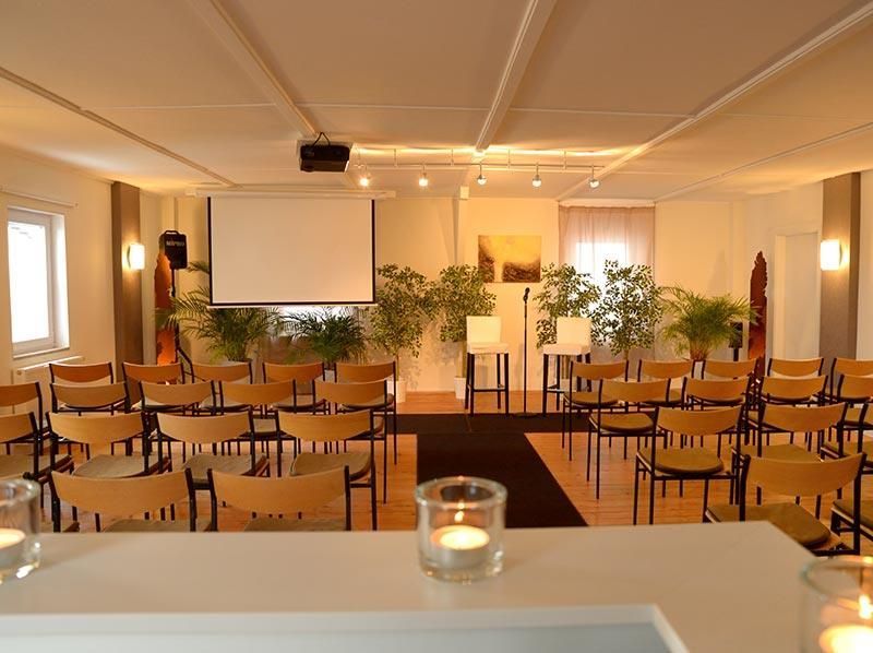 Ein großer Raum mit Stuhlreihen und einer Projektionsleinwand