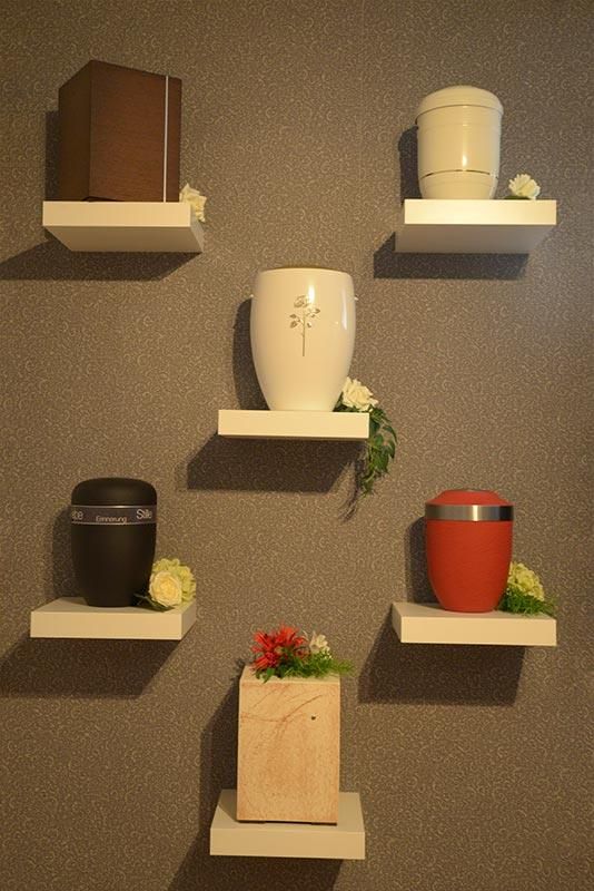 Mehrere Urnen werden auf Regalen an einer Wand ausgestellt