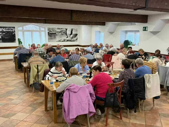 Personas sentadas en mesas en un comedor, comiendo y conversando.