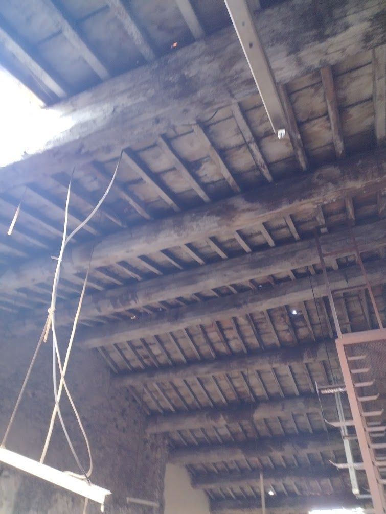 Structure de plafond en bois avec poutres sombres et panneaux à lattes, à l'intérieur d'un vieux bâtiment.