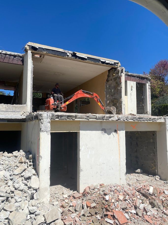 Une mini-pelle démolit un bâtiment de deux étages par une journée ensoleillée.