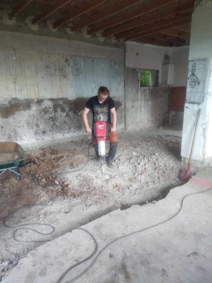 Une pelleteuse jaune charge des gravats dans un camion-benne, sur un chantier de construction.