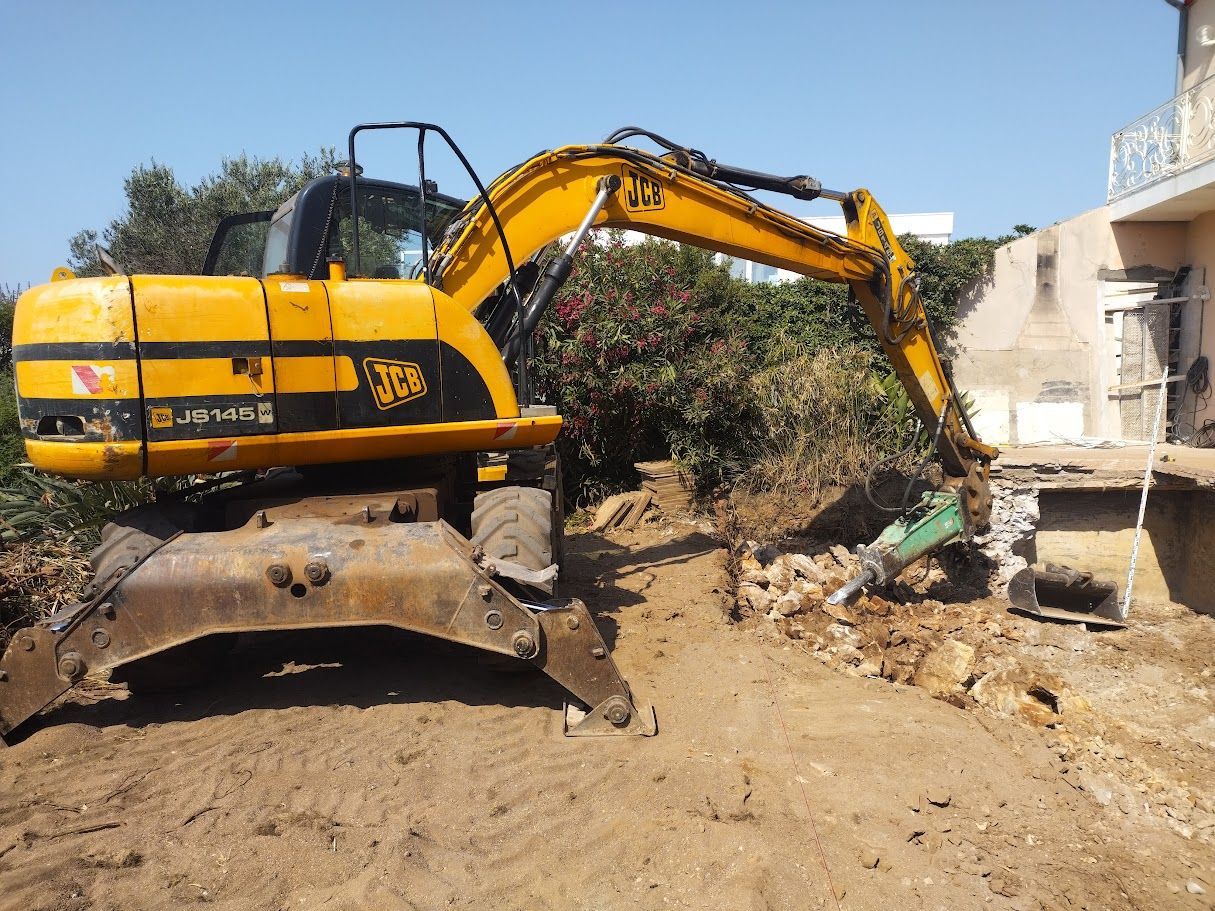 Une pelle mécanique JCB jaune démolit une structure sur un chantier de construction.