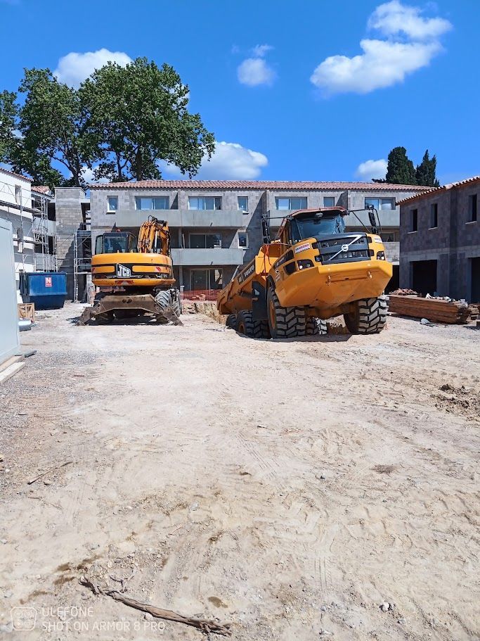 Chantier de construction avec une excavatrice creusant une tranchée ; ouvrier dans la tranchée.
