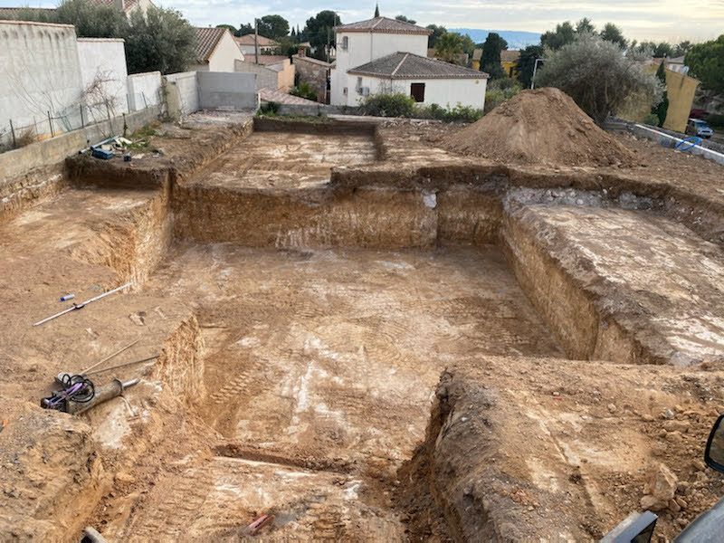 Terre excavée pour la construction d'une structure, un tas de terre et les bâtiments environnants.