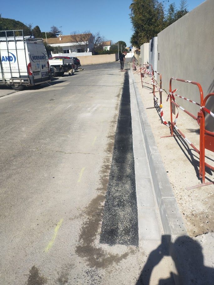 Chantier de construction avec une pelleteuse sur une allée de gravier, maison moderne en arrière-plan.