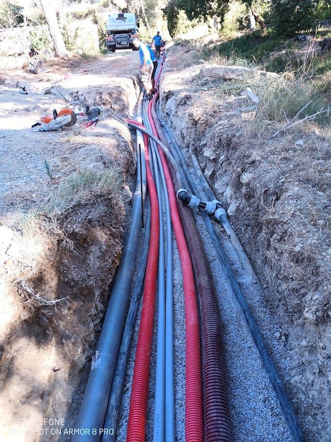 Tuyaux en PVC bleus posés sur un lit de gravier pour un système de drainage souterrain, à l'extérieur.