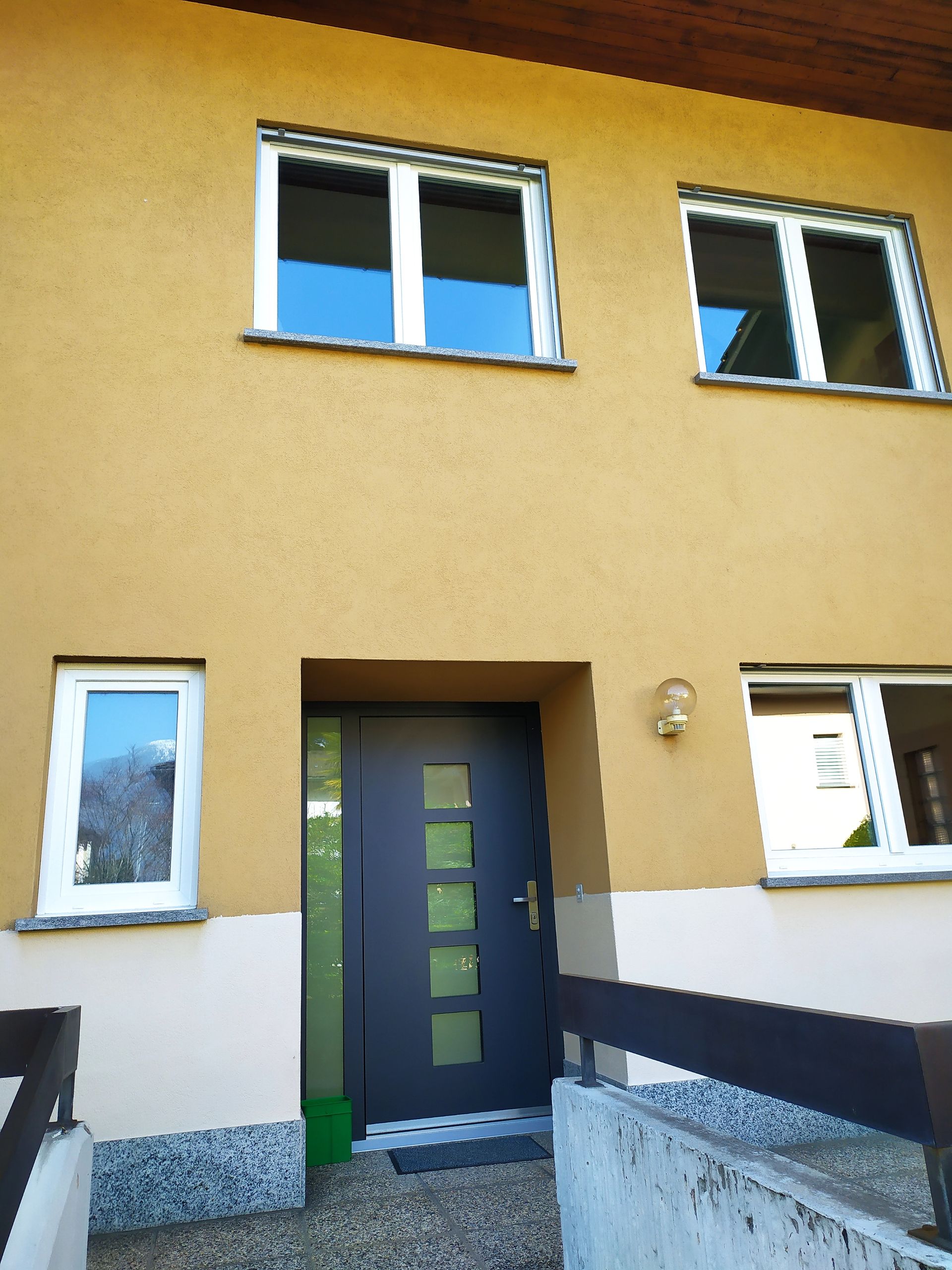 Portoncino su misura in alluminio Inotherm. Modello AK 323, triplo vetro di sicurezza, serratura a 5 punti di chiusura (con perni a gancio), maniglia di sicurezza (RC3). Fianco luce sinistro in sovrapprezzo. Finestre Budvar in PVC bianco, T-Comfort, vetri di sicurezza VSG.