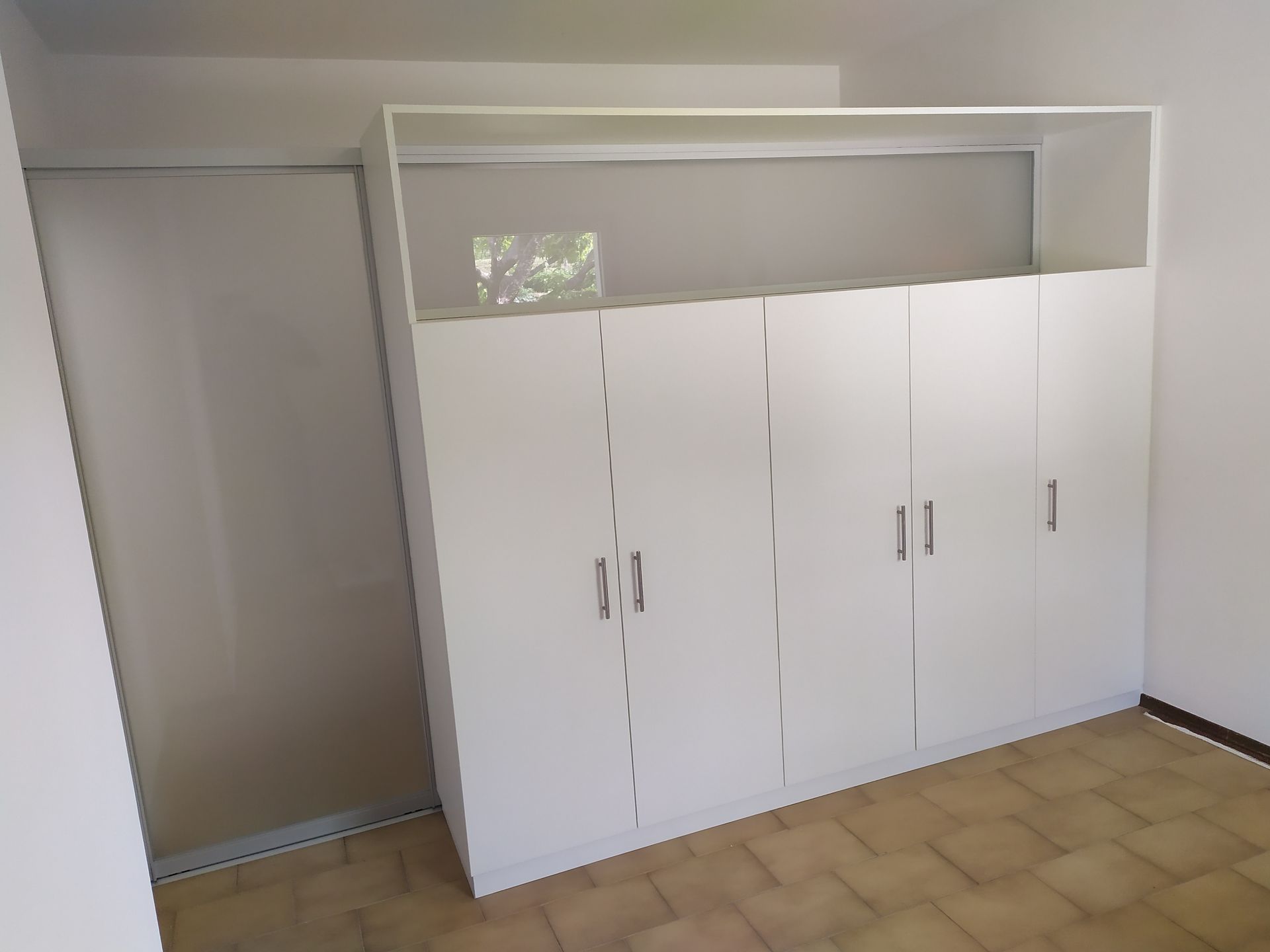 armadio bianco a 5 ante, telaio in alluminio con vetro nella parte superiore. Anta scorrevole in alluminio e vetro. In posizione aperta viene nascosta  nell'intercapedine dell'armadio. (vetri di sicurezza satinati bianchi)