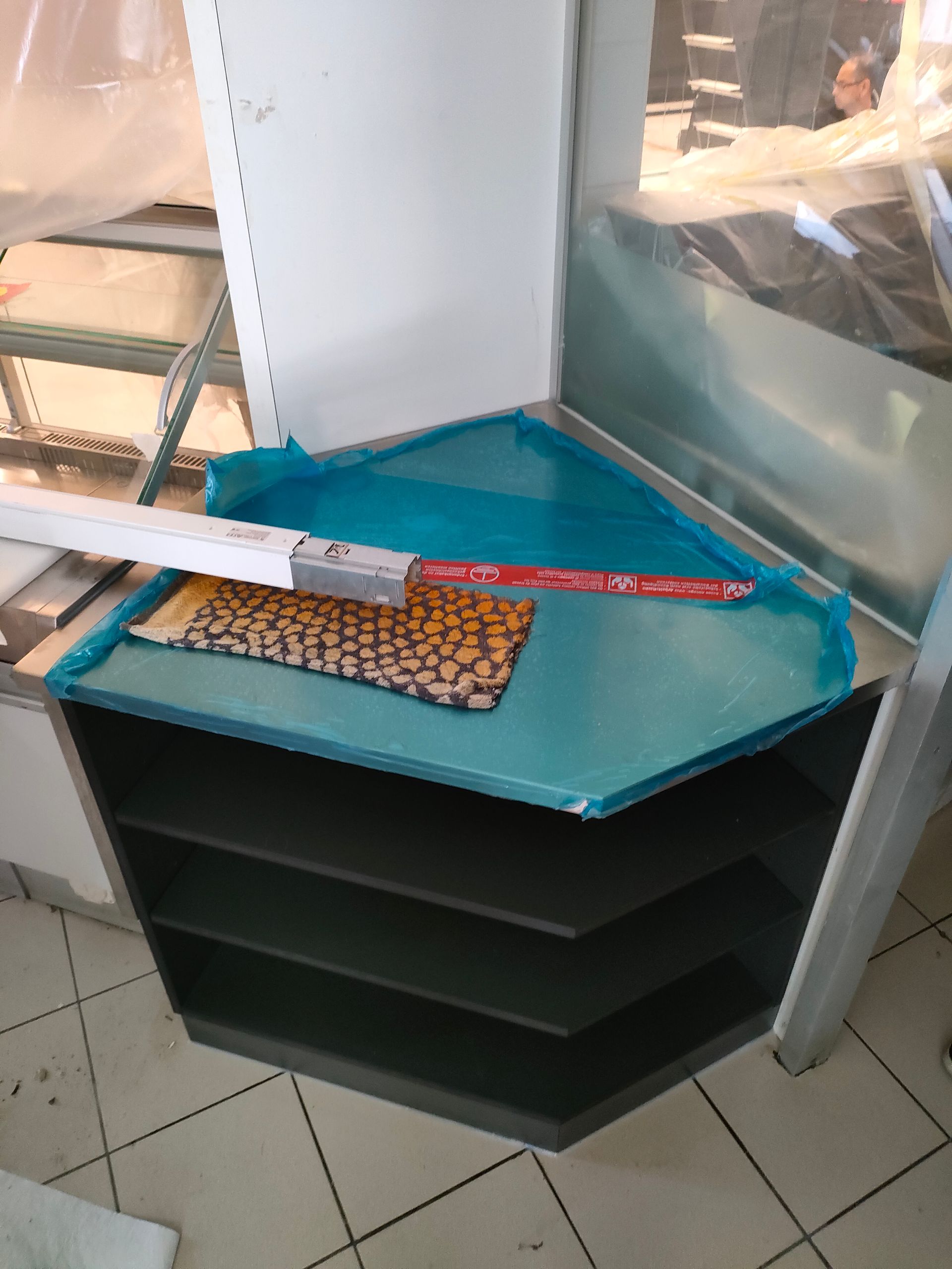 Arredamento negozio. Mobile d'angolo. Esecuzione su misura con materiale Swiss Krono - SwissCDF grigio U164 PE, resistente all'umidità, spessore 19.4 mm. Parti interne a vista con 2 ripiani. 
Zoccolo con parti frontali chiuse.
Rivestimento piano superiore in acciaio inox con risvolti.