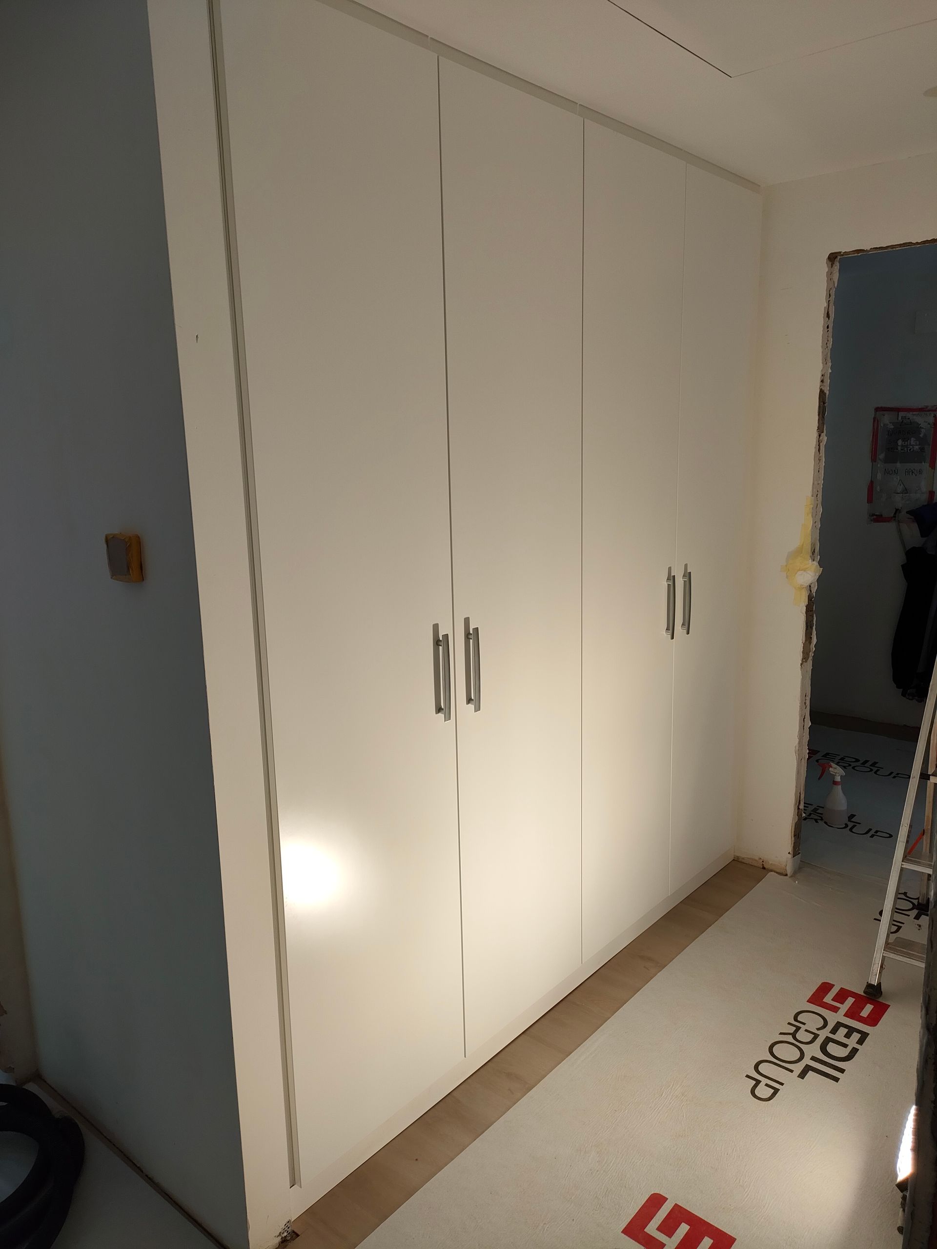 armadio a muro con 4 ante laccate bianco RAL 9016. Parte destra con cassonetto copri tubi. Cerniere nascoste con chiusura ammortizzata. Luci led incassate con sensore di movimento. Maniglie Colombo