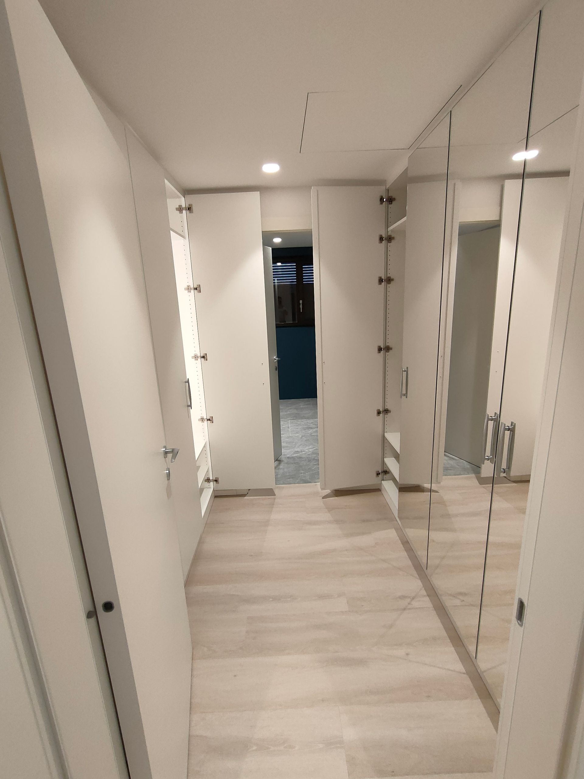 armadi a muro su 2 lati del locale. Un lato 4 ante laccate bianco RAL 9016, lato  opposto ante laccate con 4 specchi. Cerniere nascoste con chiusura ammortizzata. Luci led incassate con sensore di movimento. Maniglie Colombo