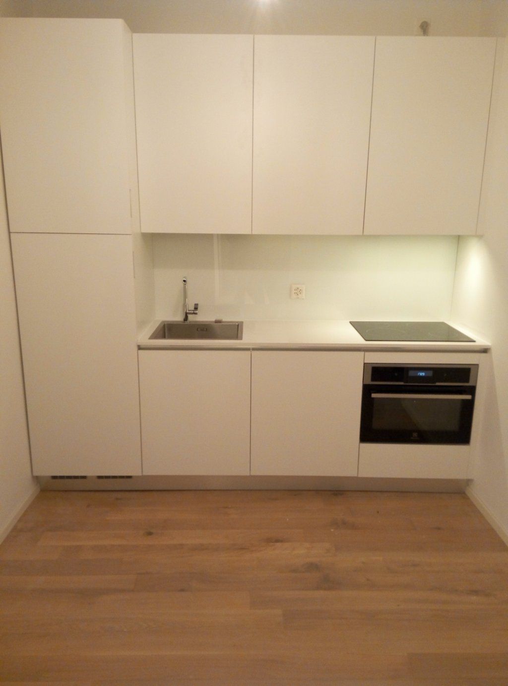 cucina per ufficio, piano in corian, ante SwissKrono bianco, vetro bianco lucido a parete