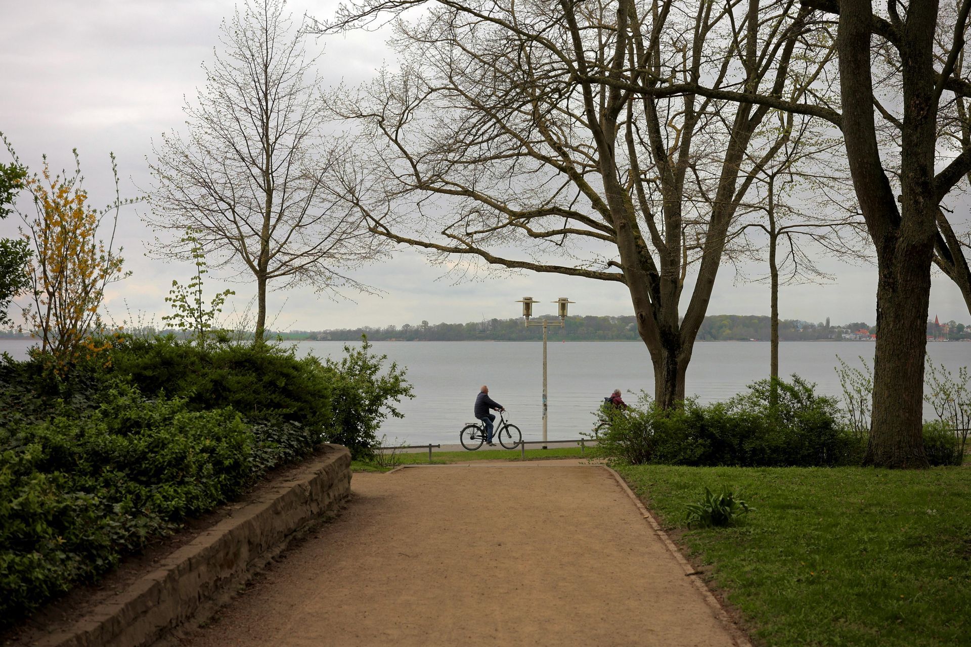 Eine Person fährt mit dem Fahrrad einen Weg in der Nähe eines Sees entlang