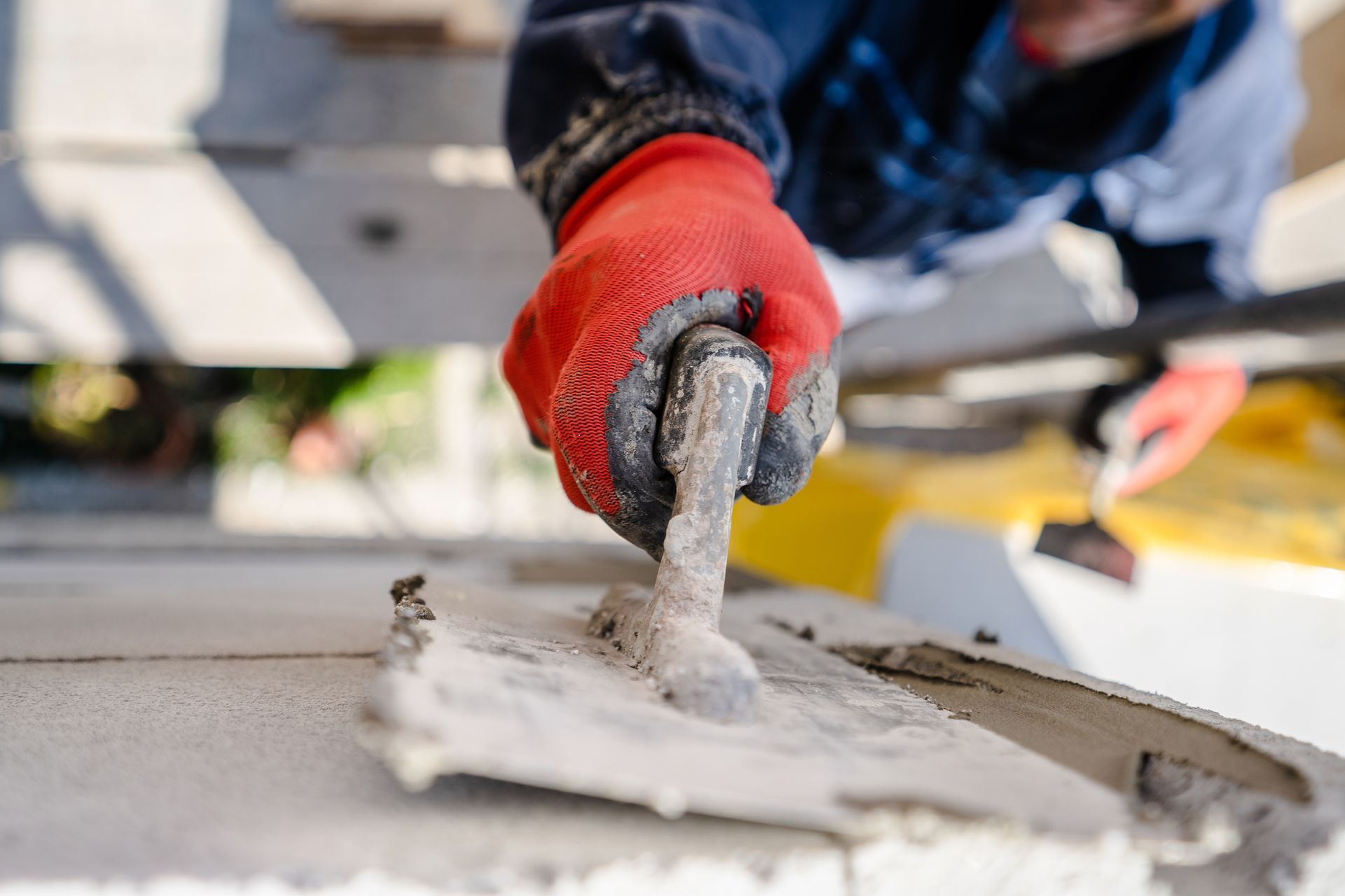 Ouvrier du bâtiment enduisant un mur avec du mortier de ciment à la truelle 