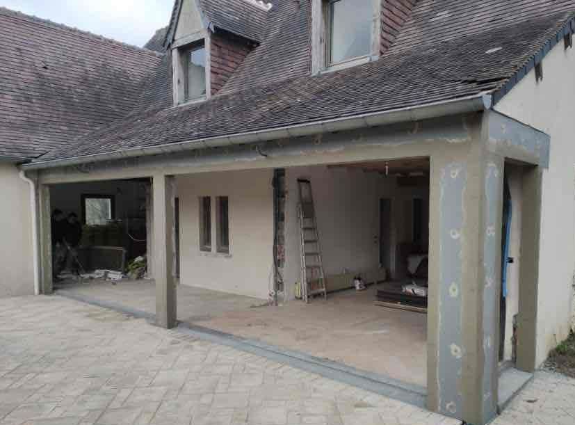 Maison individuelle avec gros plan sur une table présentant des plans et des casques de chantier