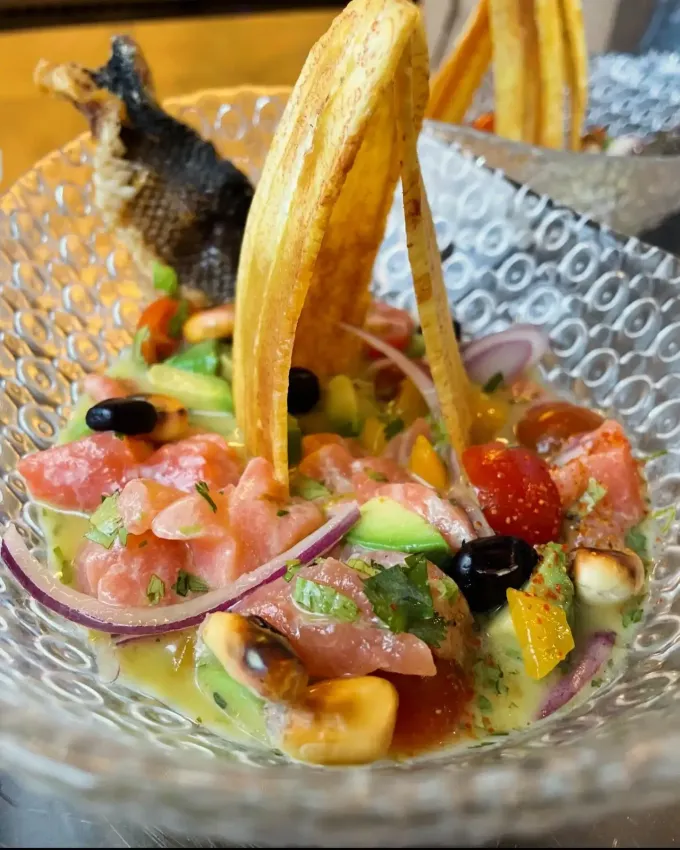 Salsa colorida en un cuenco de vidrio con tiras de tortilla, aceitunas y totopos