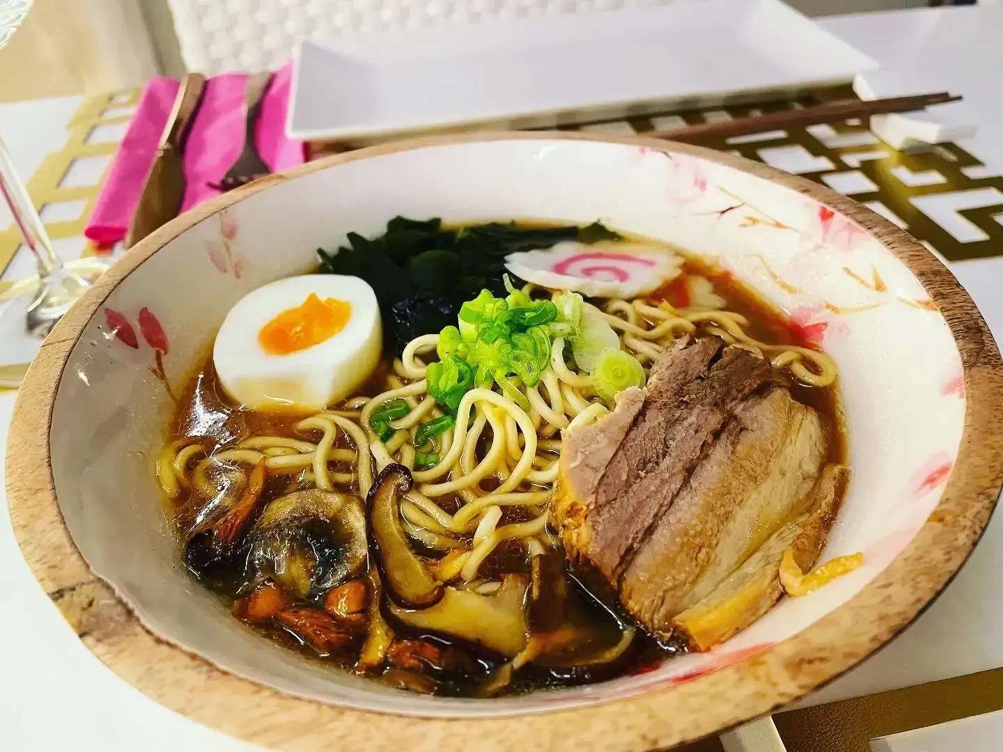 Cuenco de ramen con cerdo en lonchas, huevo pasado por agua, algas y cebolleta sobre una mesa