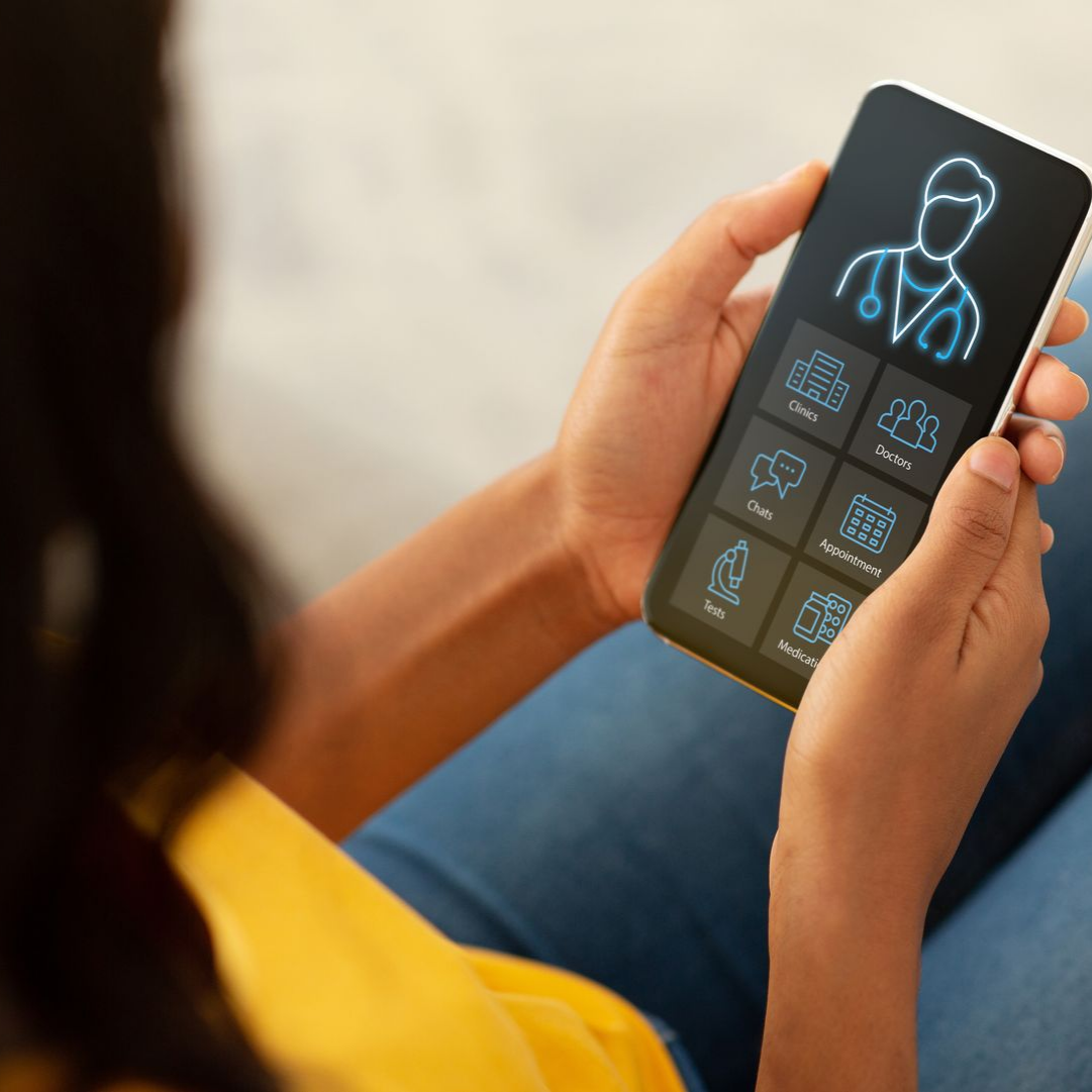 Personne tenant un smartphone affichant une icône de médecin, assise sur un canapé