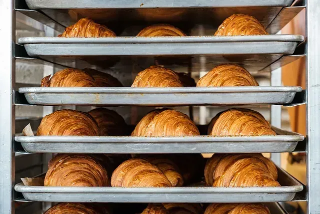 Un montón de croissants están colocados en una rejilla en una panadería.