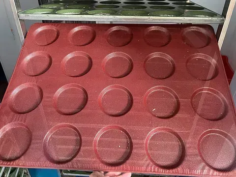Una bandeja roja con círculos está colocada encima de un estante.