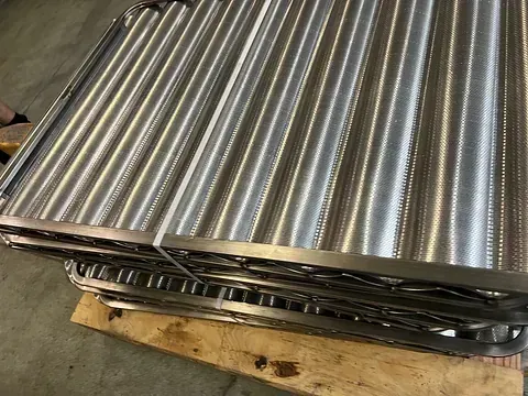 Una pila de tubos de acero inoxidable colocada encima de una paleta de madera.