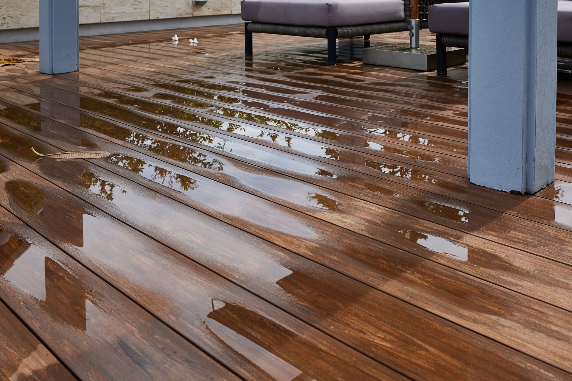 Des flaques d'eau sur un plancher en bois avec des poteaux de soutien.