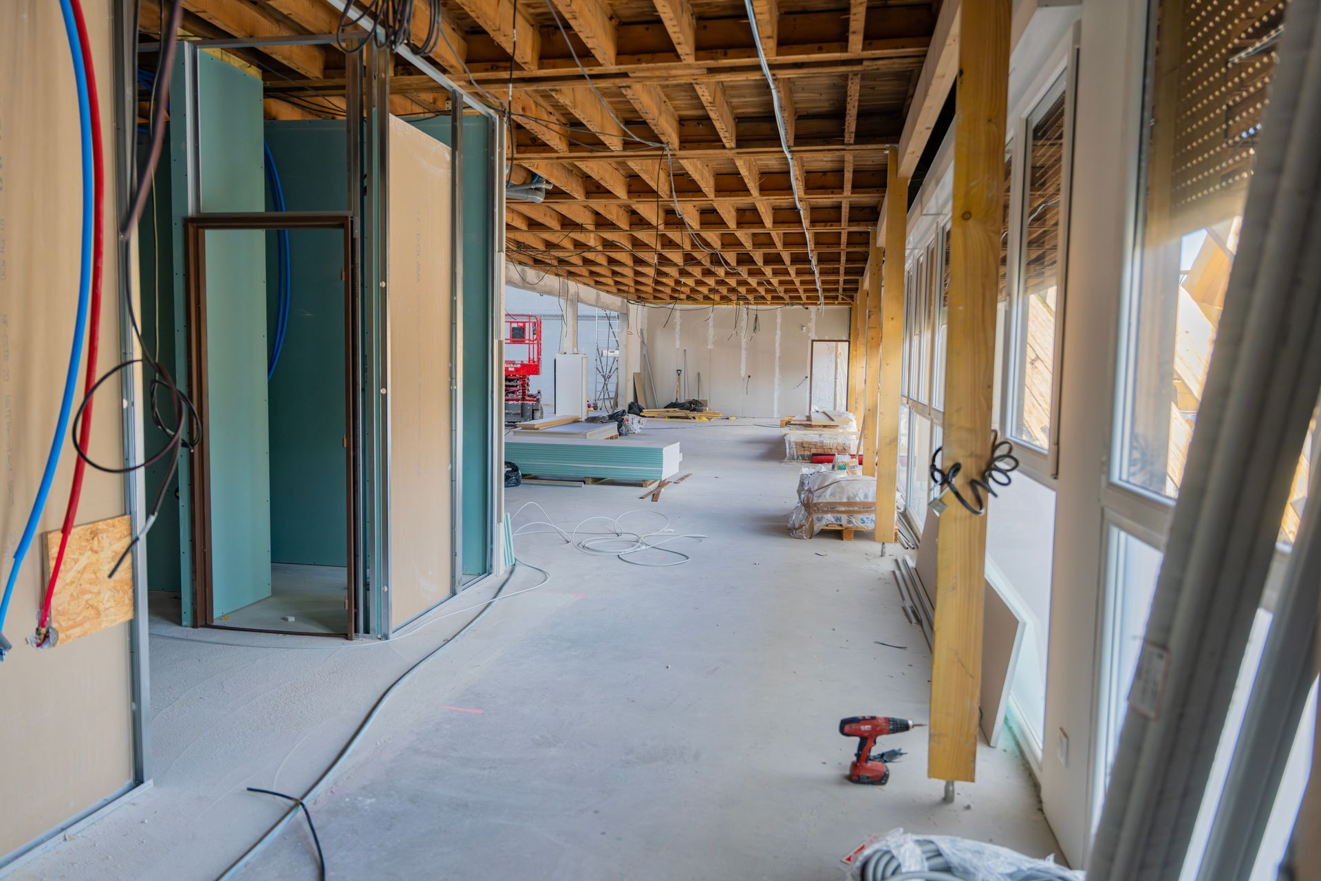 Vue d'un chantier en intérieur, avec des solives de plafond en bois apparentes et des murs en construction