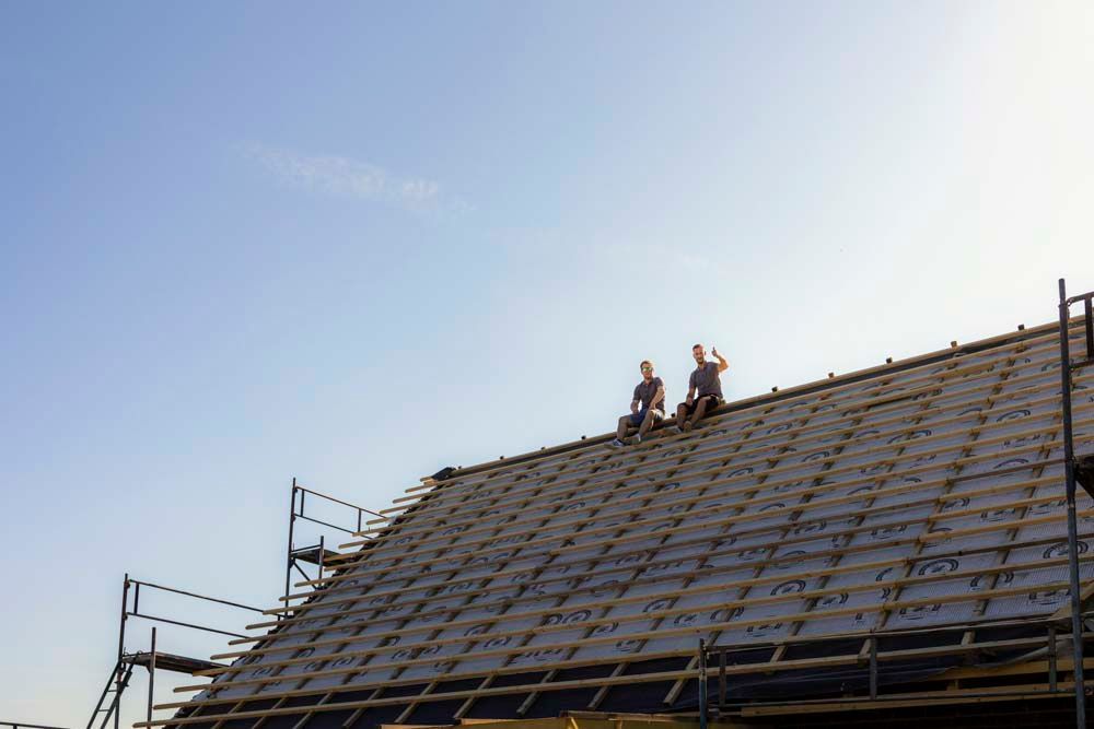 Zwei Männer sitzen auf dem Dach eines im Bau befindlichen Gebäudes.