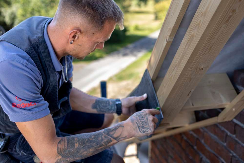 Ein Mann misst ein Stück Holz mit einem Maßband.