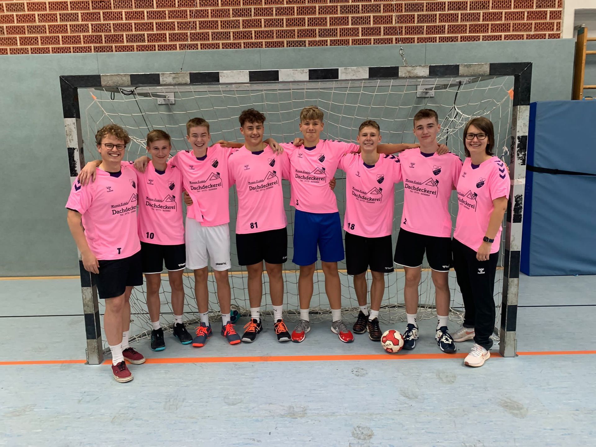 Eine Gruppe junger Männer in rosa Hemden posiert vor einem Tor für ein Foto.