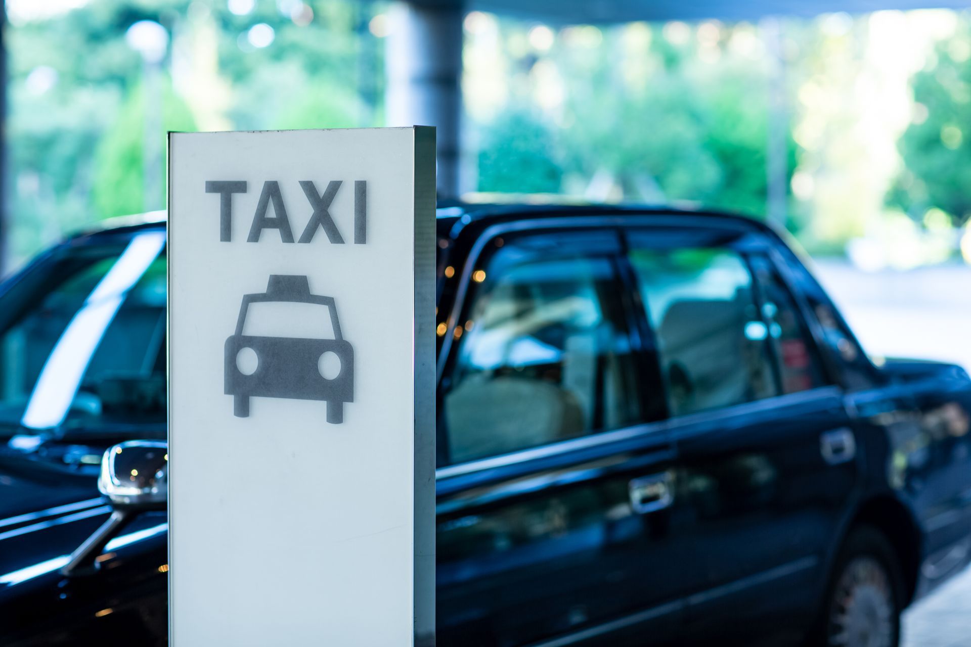 Voiture noire derrière une pancarte avec le logo taxi dessus