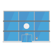 Edificio moderno con grandes ventanales de vidrio azul, barras horizontales grises y un detalle circular blanco.